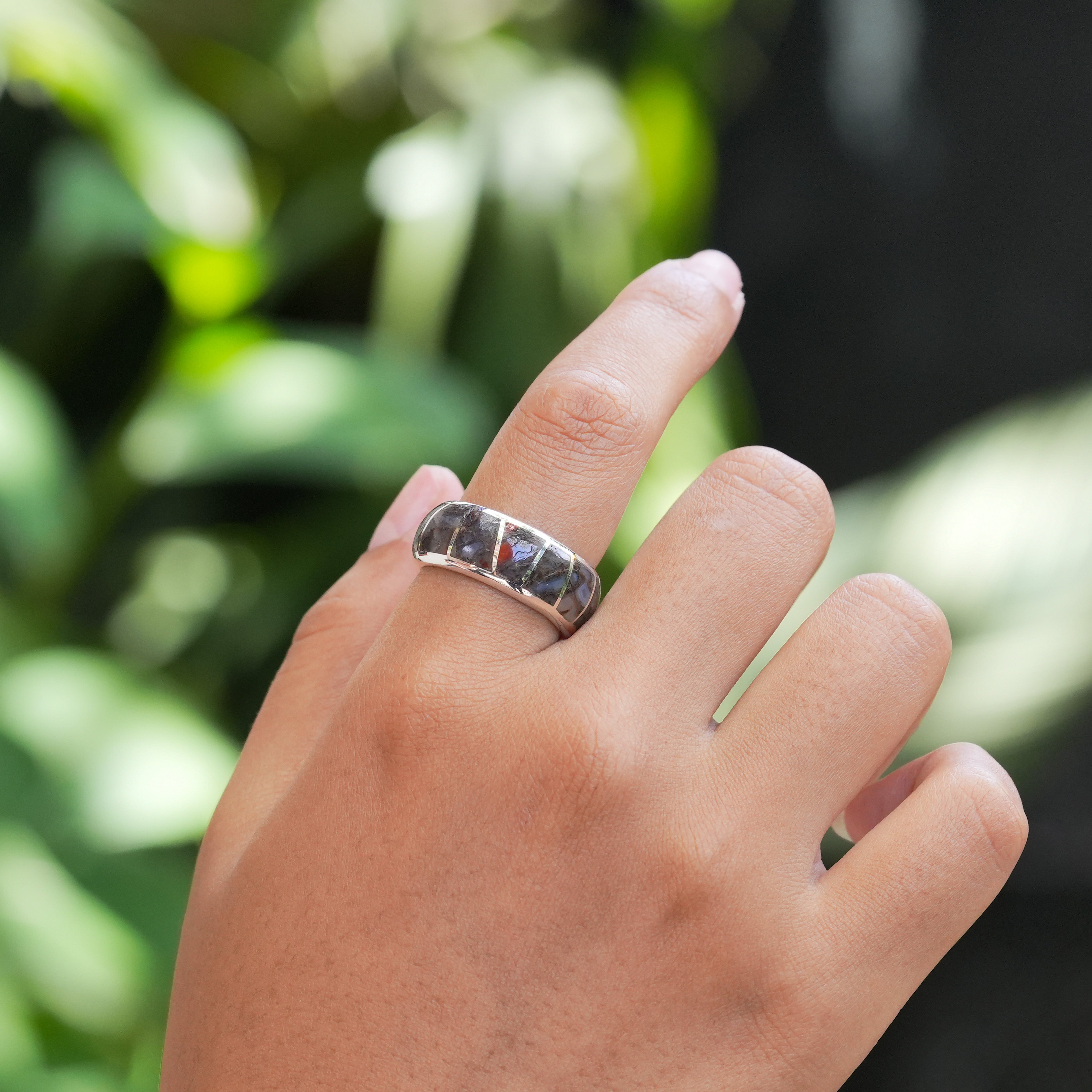 Sterling silver channel ring with fossil dinosaur bone inlay worn on a finger to demonstrate fit. 